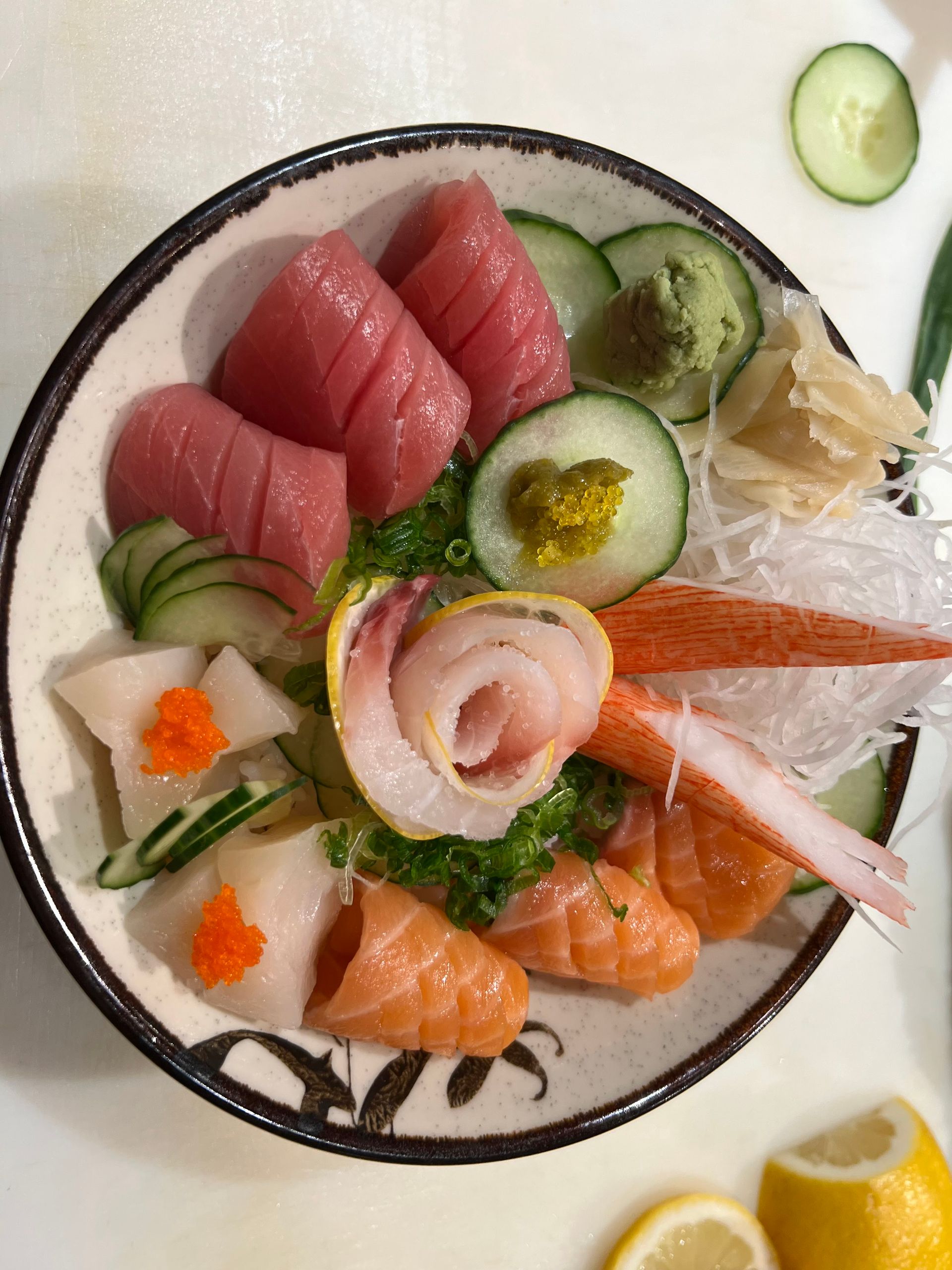 A bowl of food with vegetables and meat on a table.
