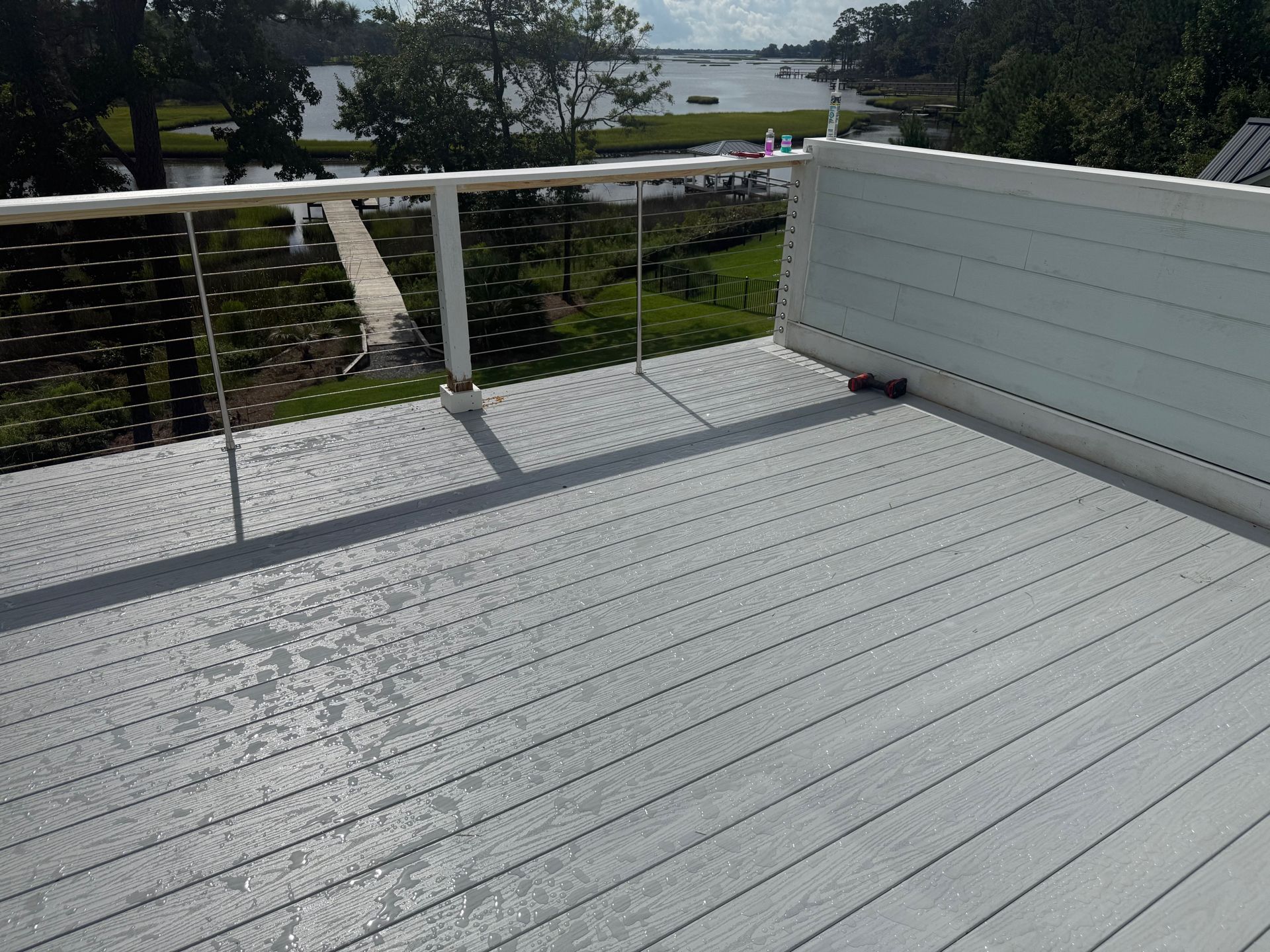 Gray deck overlooking a waterway with white railings.