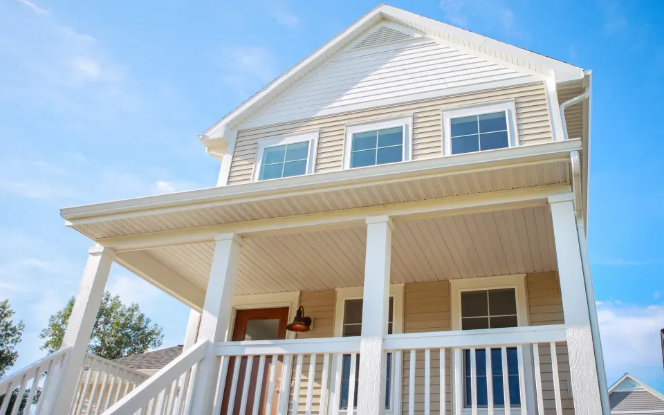 Two-story house with light blue siding, white garage door, and green lawn.