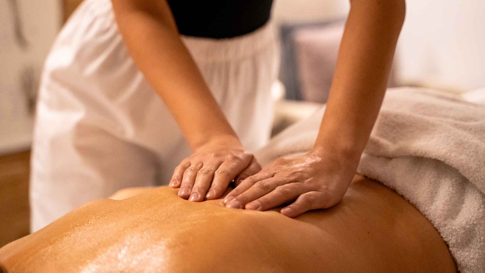 A woman is laying on a bed getting a massage from a man.