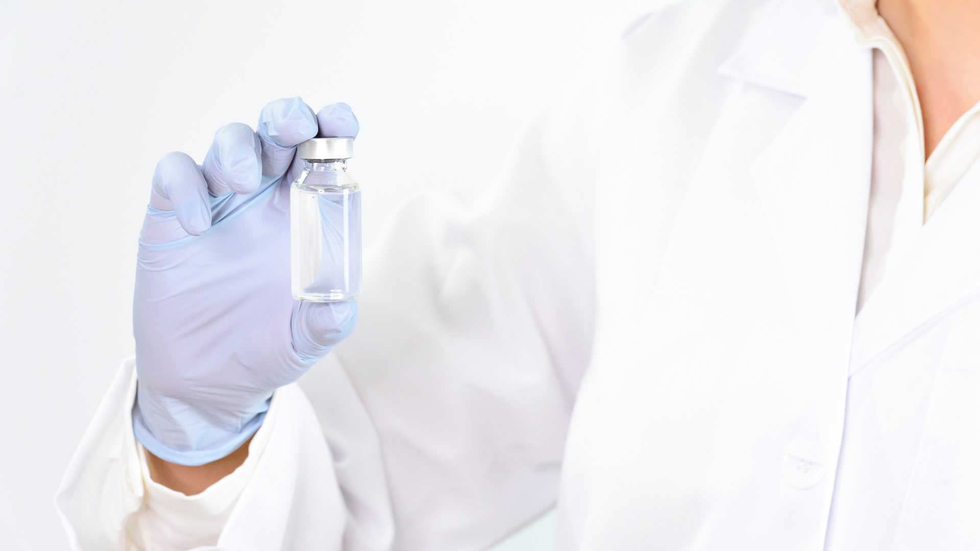 A person is holding a bottle of liquid and a syringe.