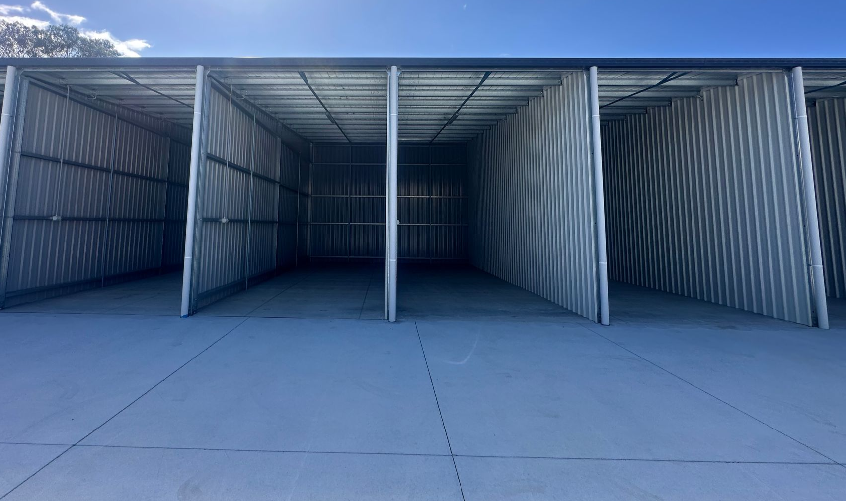 Open, Empty Storage Units With Corrugated Metal Walls Under a Bright Sky — Midcoast Premium Caravan Storage in Forster, NSW