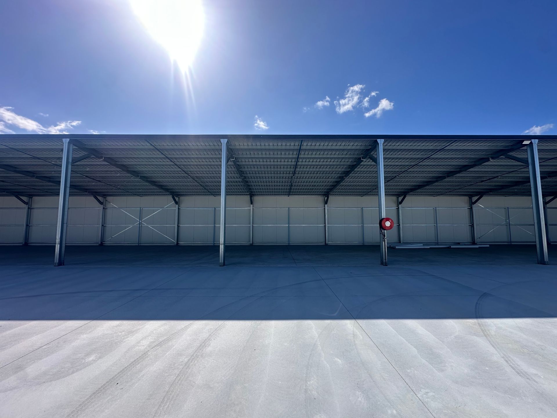 Empty Blue Warehouse With A Person In A Red Shirt Standing Under A Metal Canopy — Midcoast Premium Caravan Storage in Forster, NSW