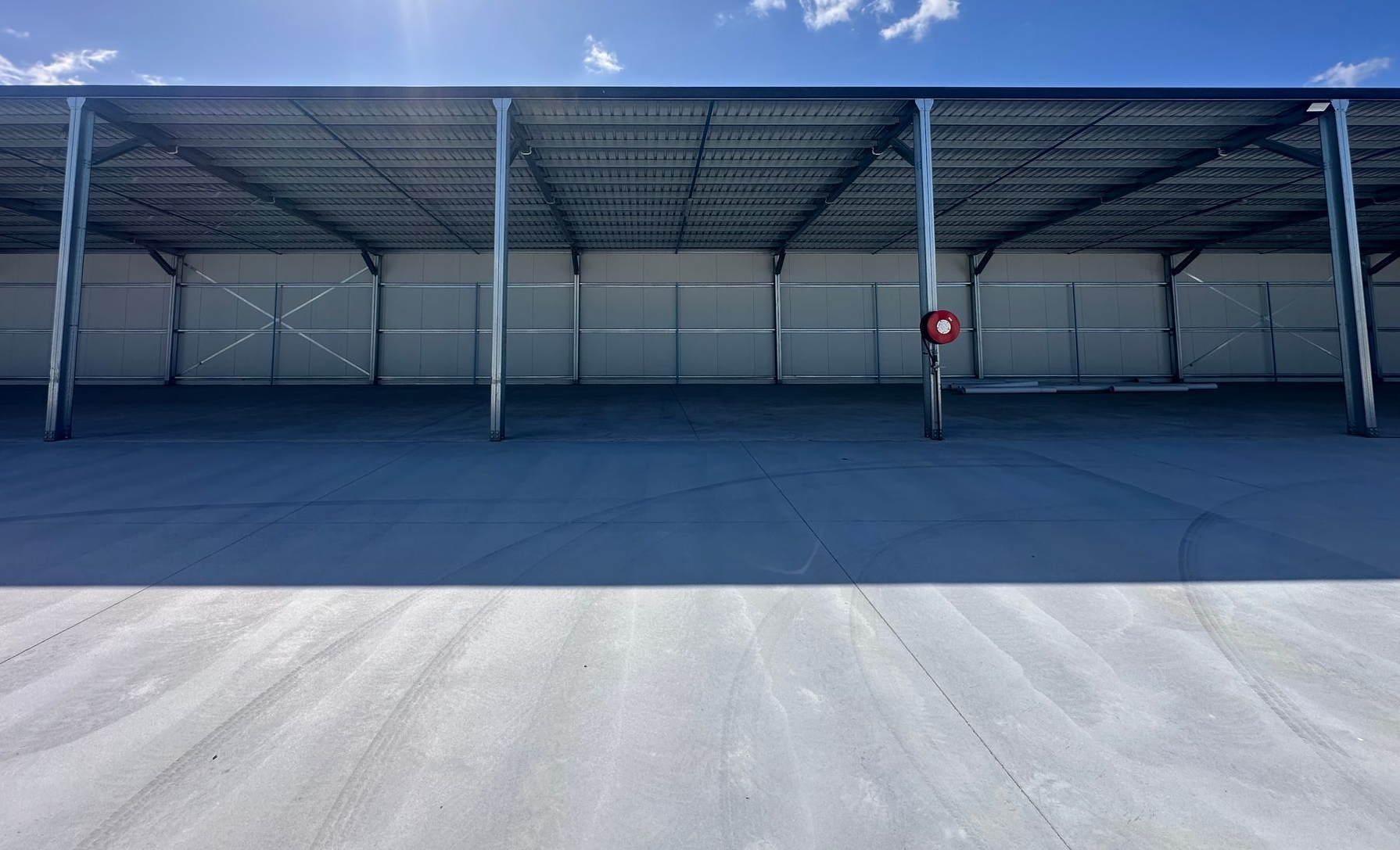 Empty covered parking structure with a red sign under a blue sky