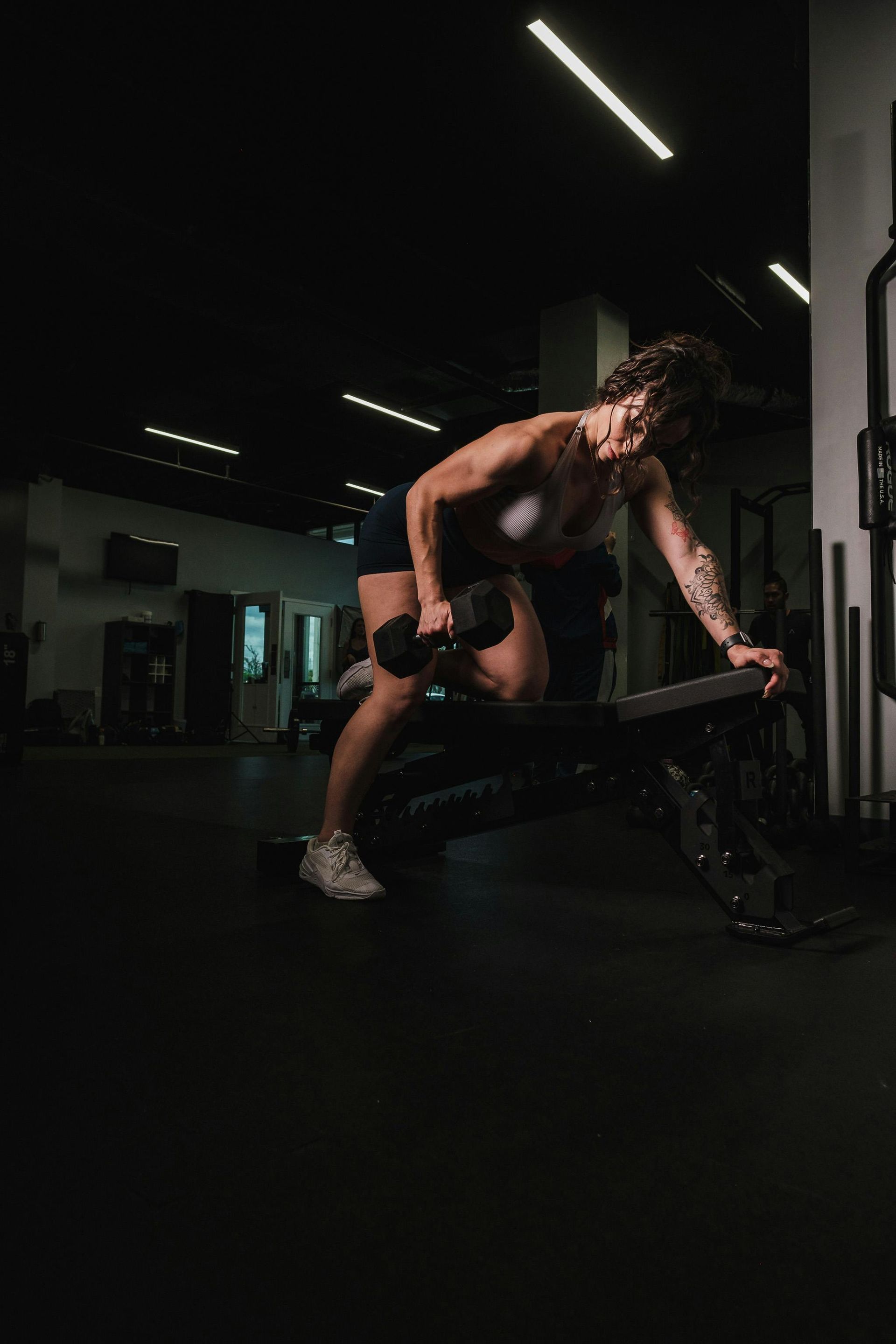 Woman doing dumbbell row on a bench in ethos fitness la.