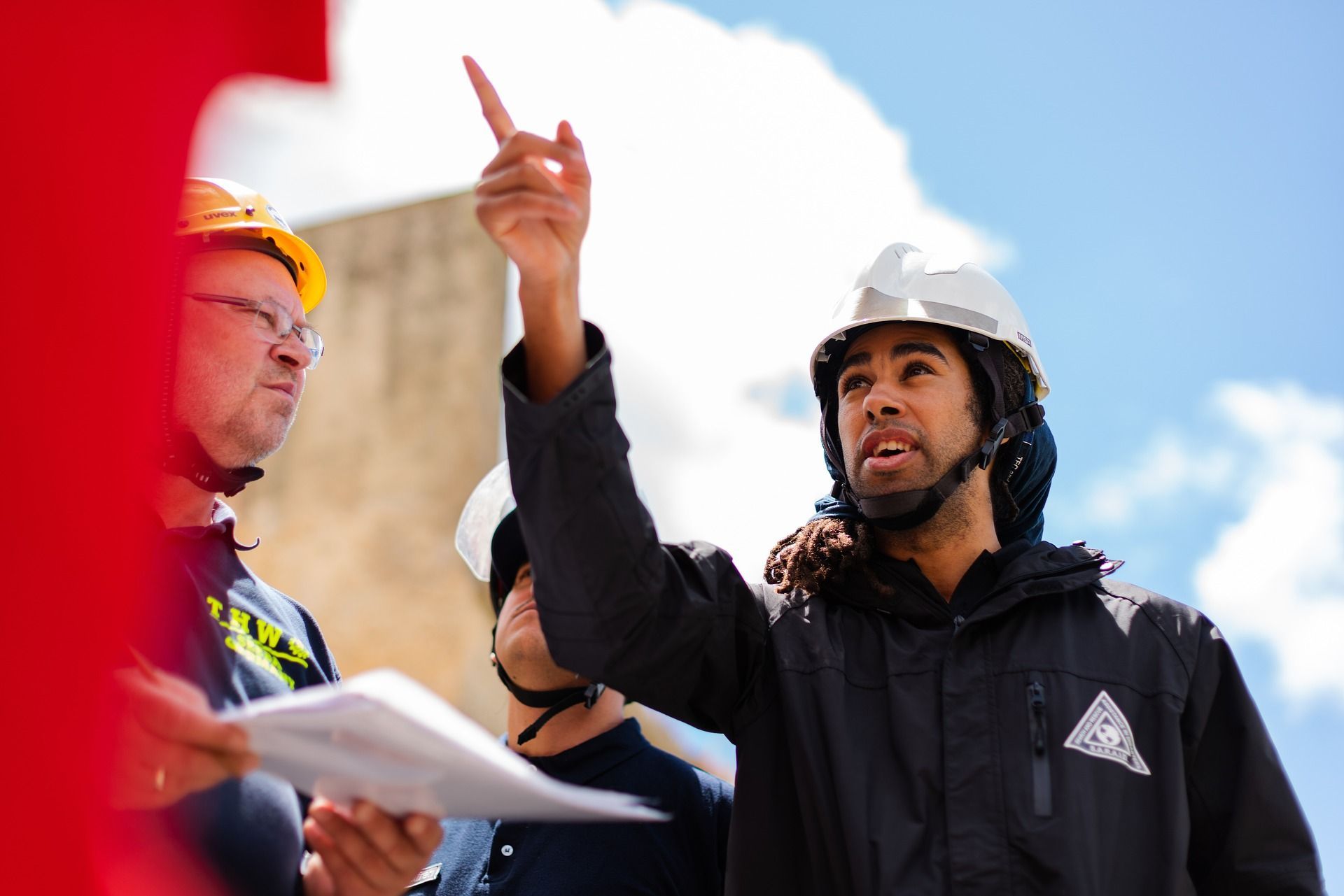 Photograph of an engineer with a raised hand, pointing skywards and surrounded by other engineers.