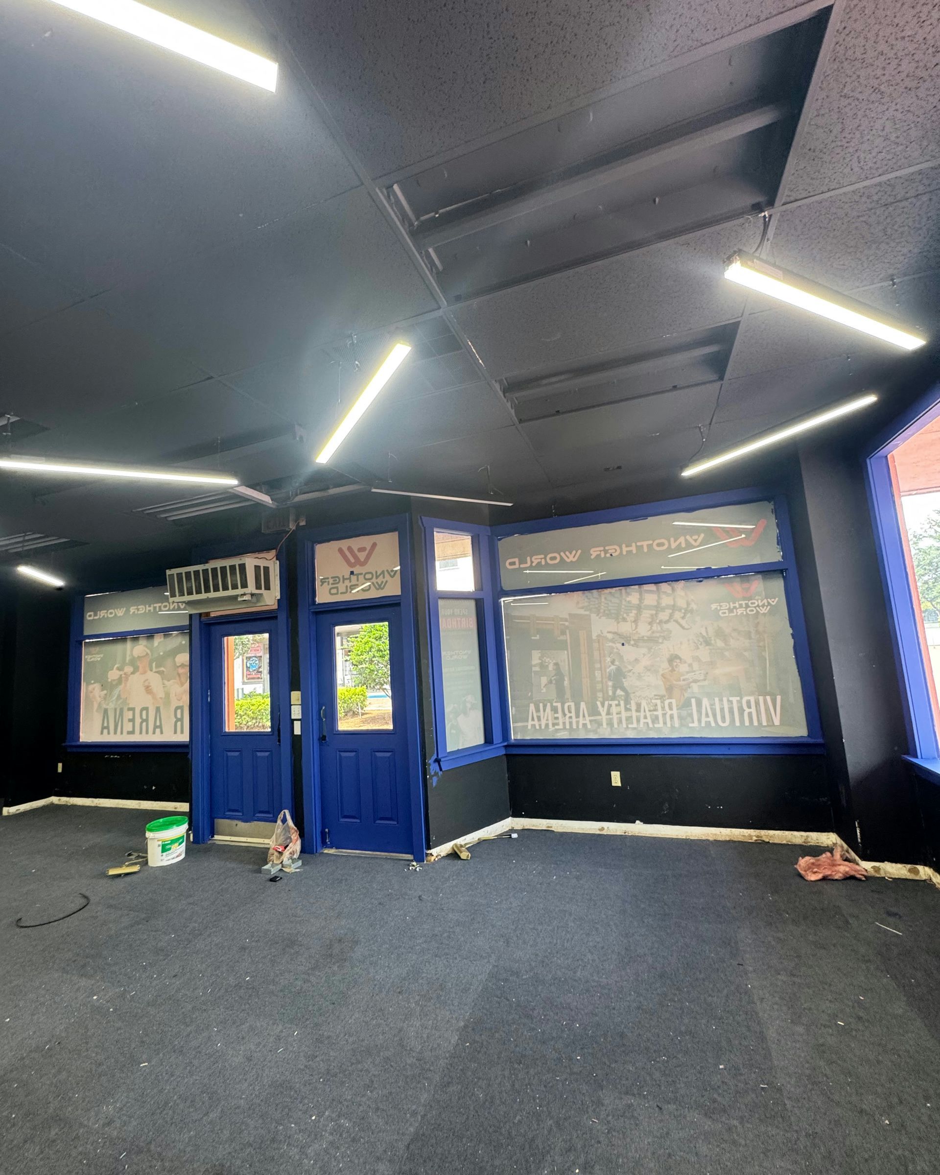 Empty room with black carpet, blue doors, and ceiling lights, showing a partially finished interior.
