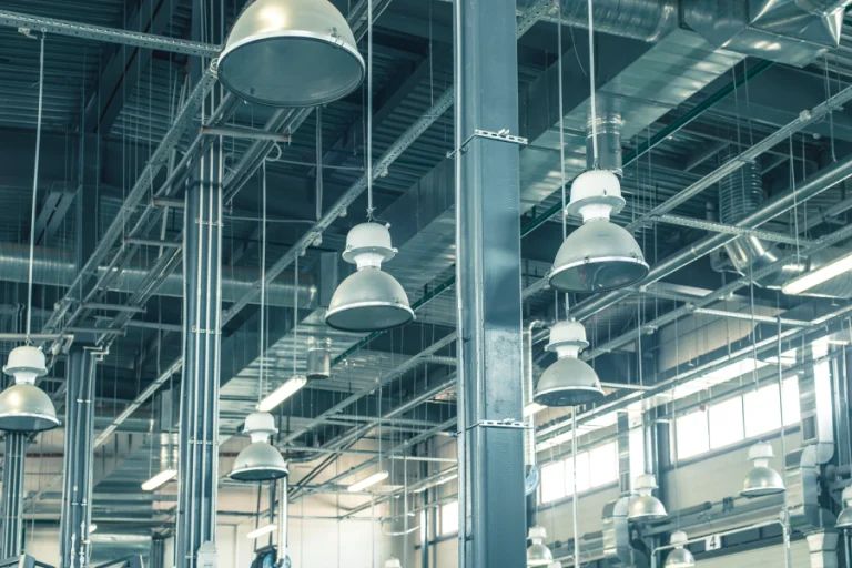 Industrial warehouse interior with hanging dome lights, steel beams, and large windows
