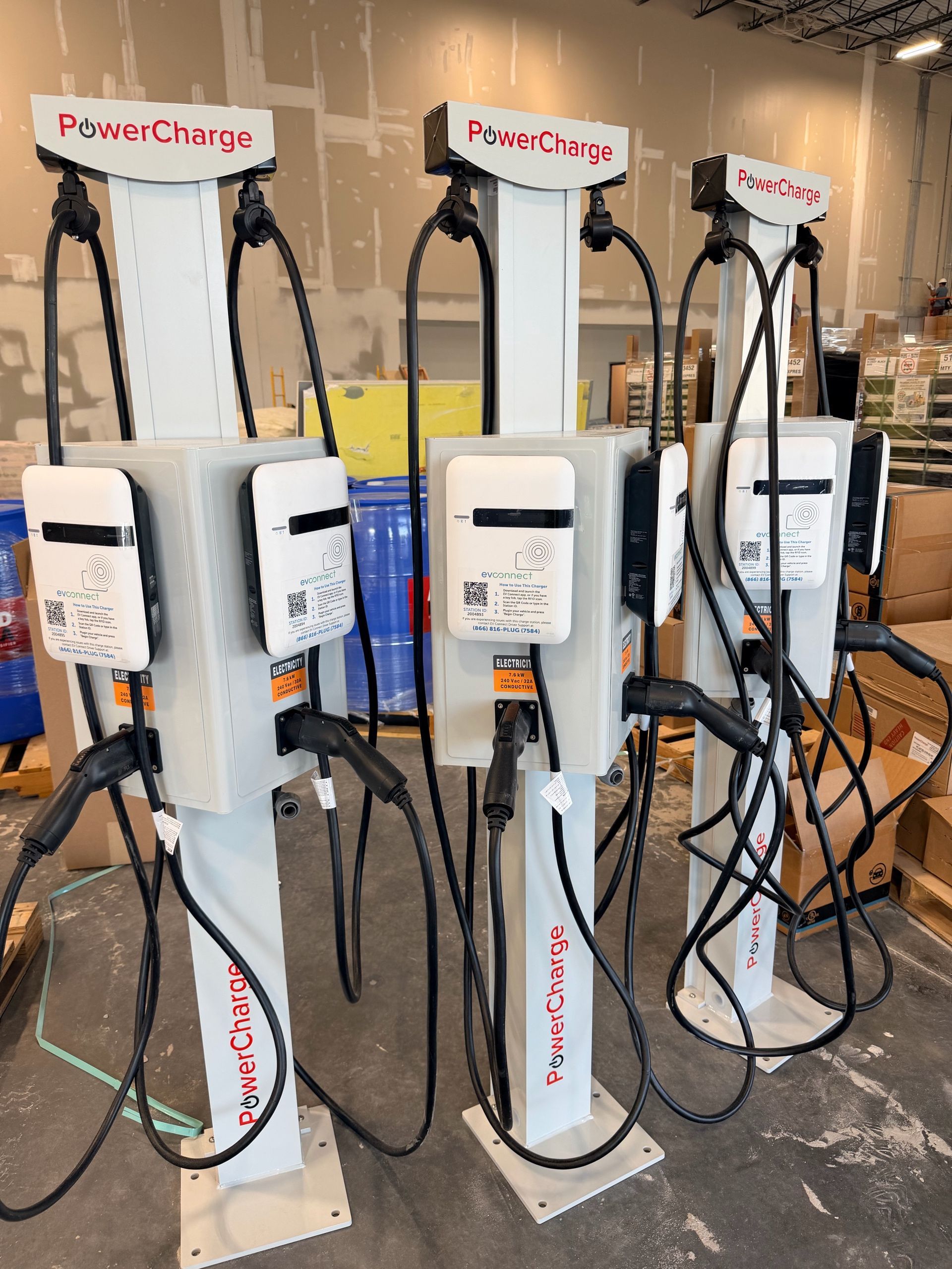 Three electric vehicle charging stations with cables in an indoor parking area
