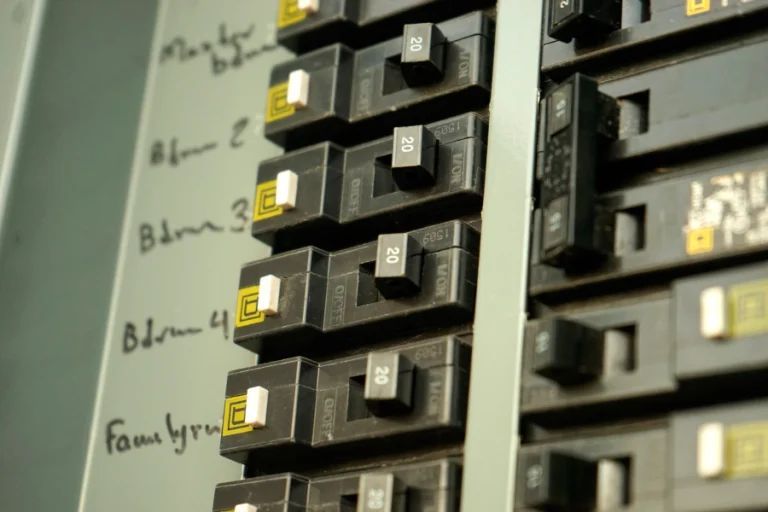Close-up of electrical breaker switches in a panel, labeled with handwritten notes on the left.