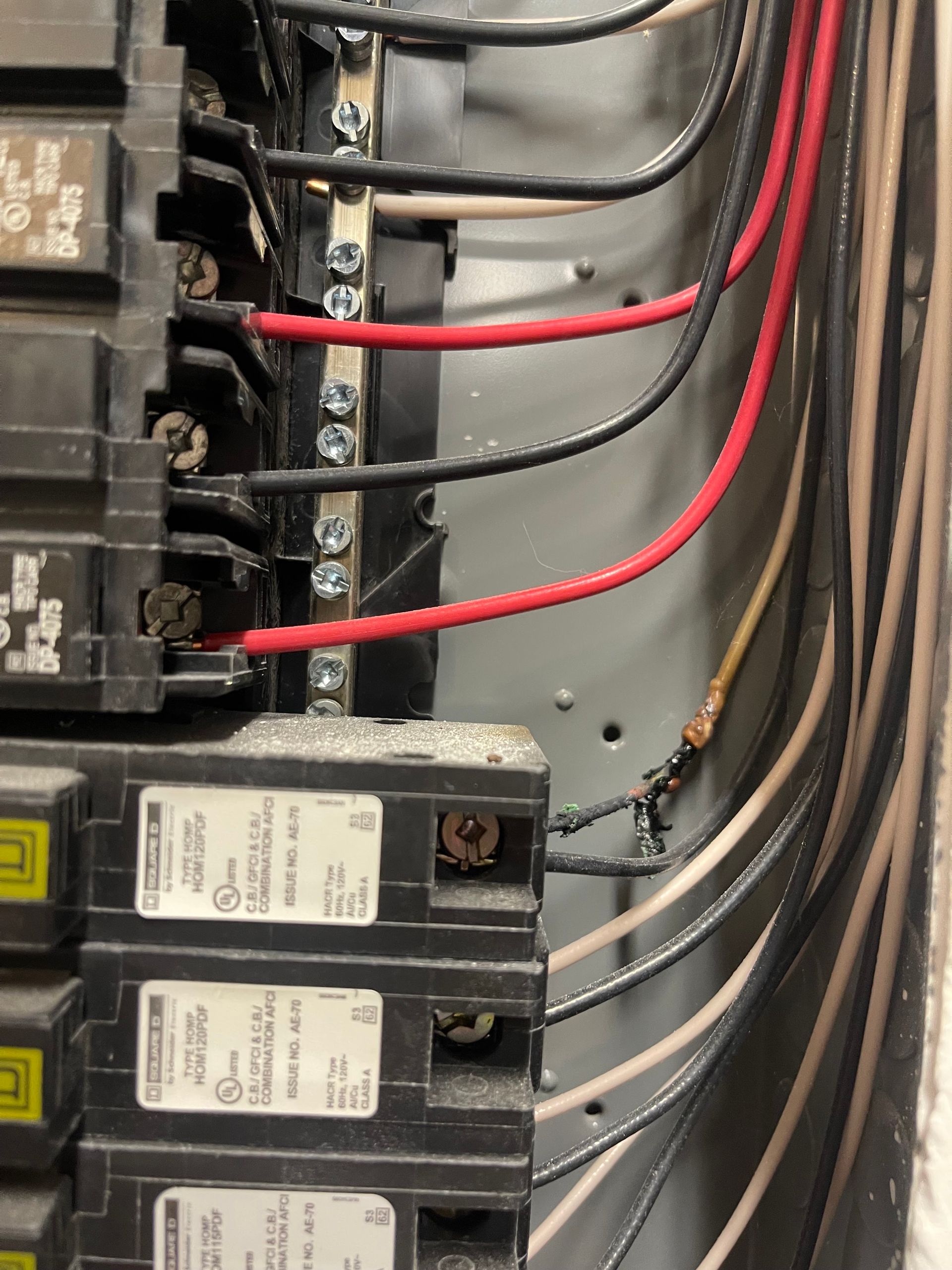 Electrical breaker panel with black breakers and red, white, and black wires connected inside.