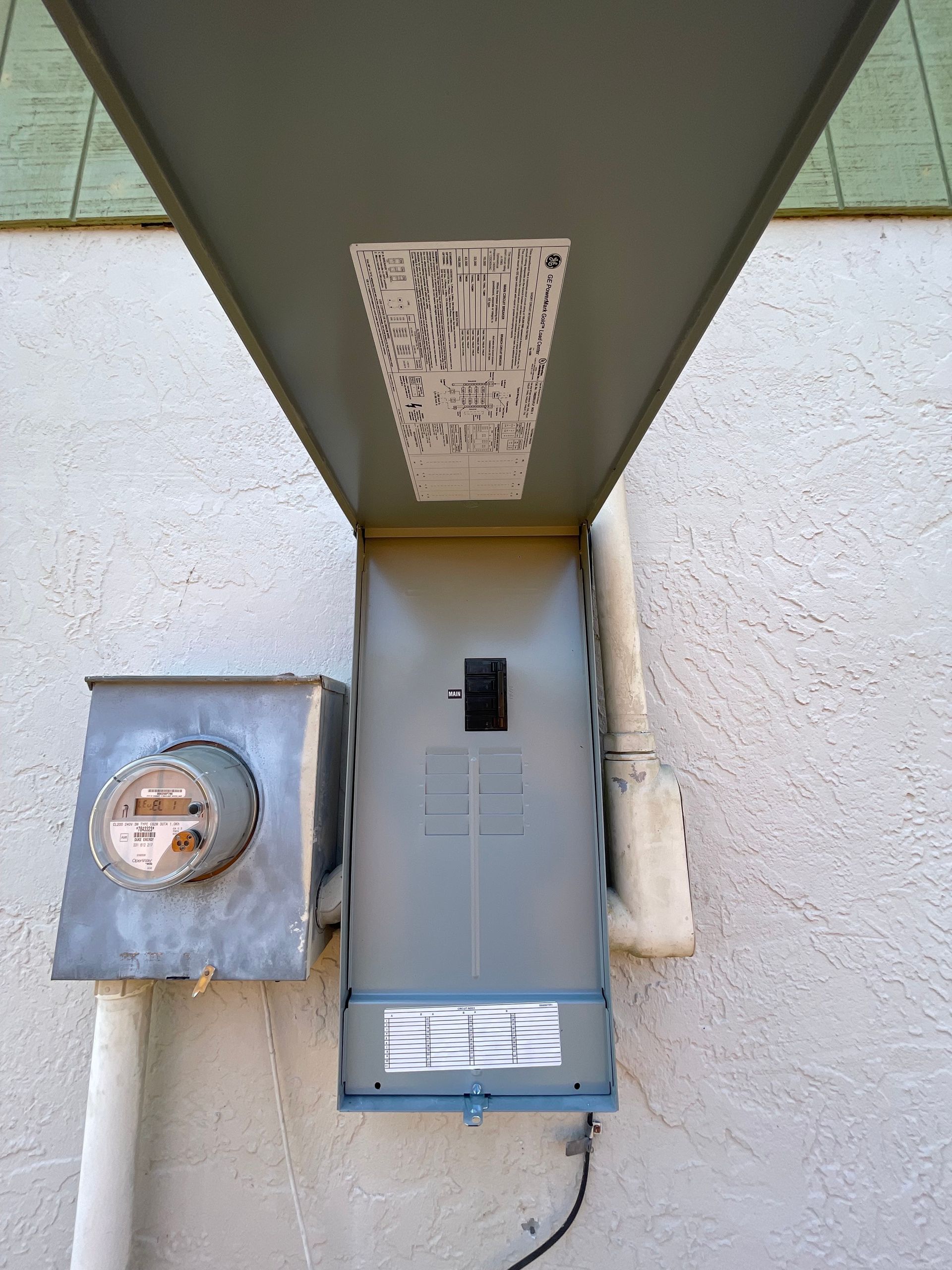 Electrical meter and utility box mounted on an exterior wall under a covered overhang.