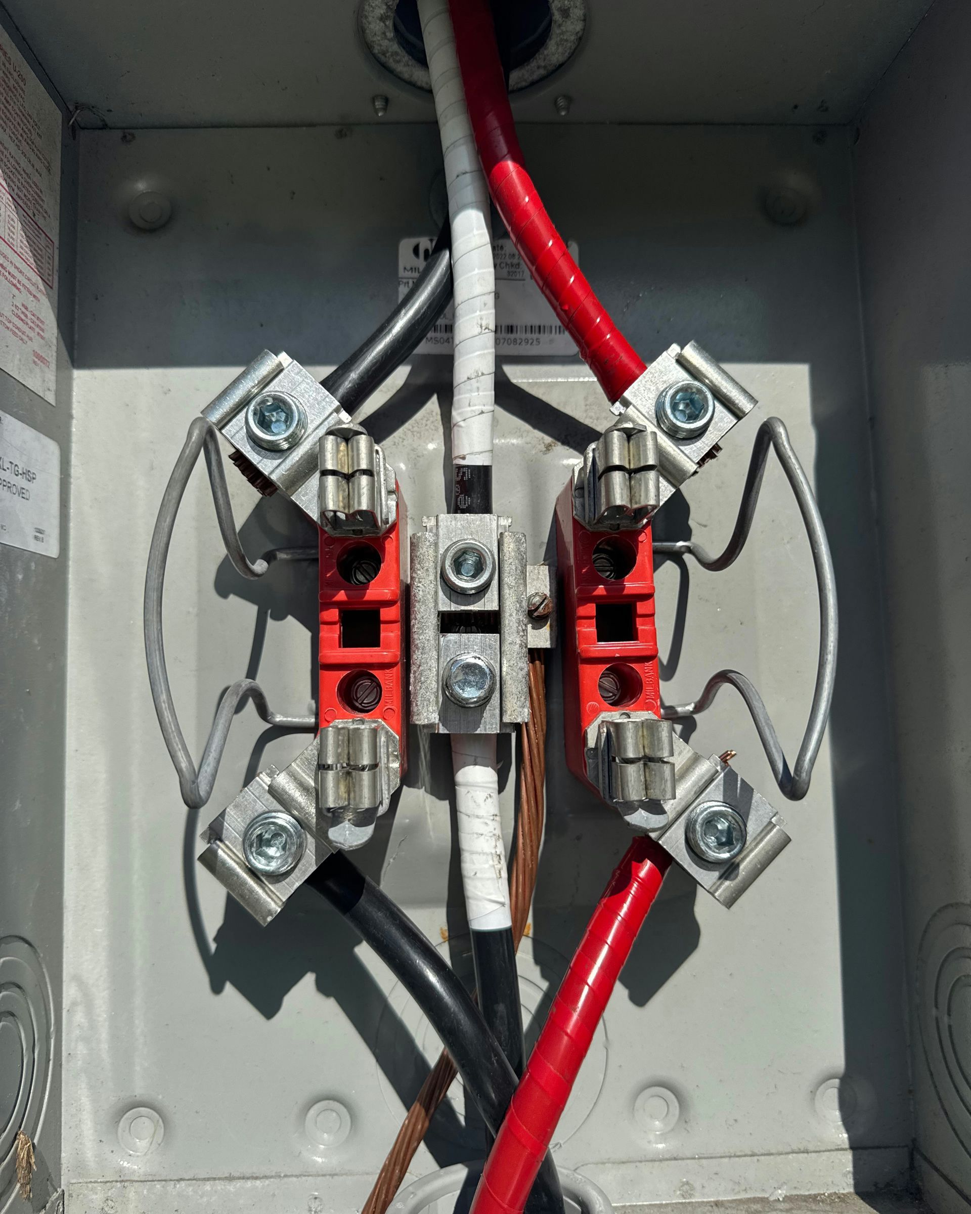 Electrical panel wiring with red and black cables connected to terminal blocks inside a metal box