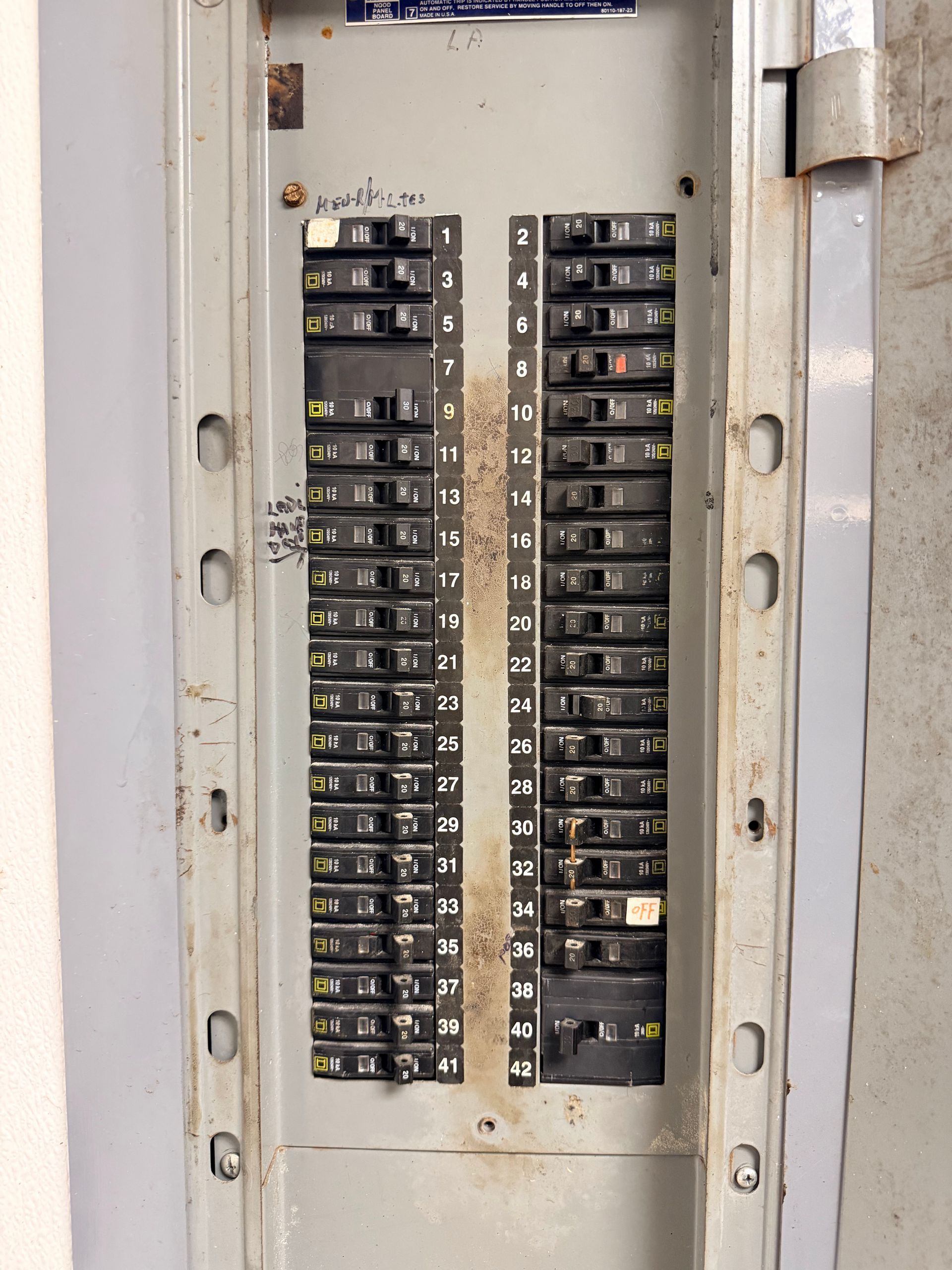 Open electrical breaker panel with rows of black circuit switches in a metal cabinet.