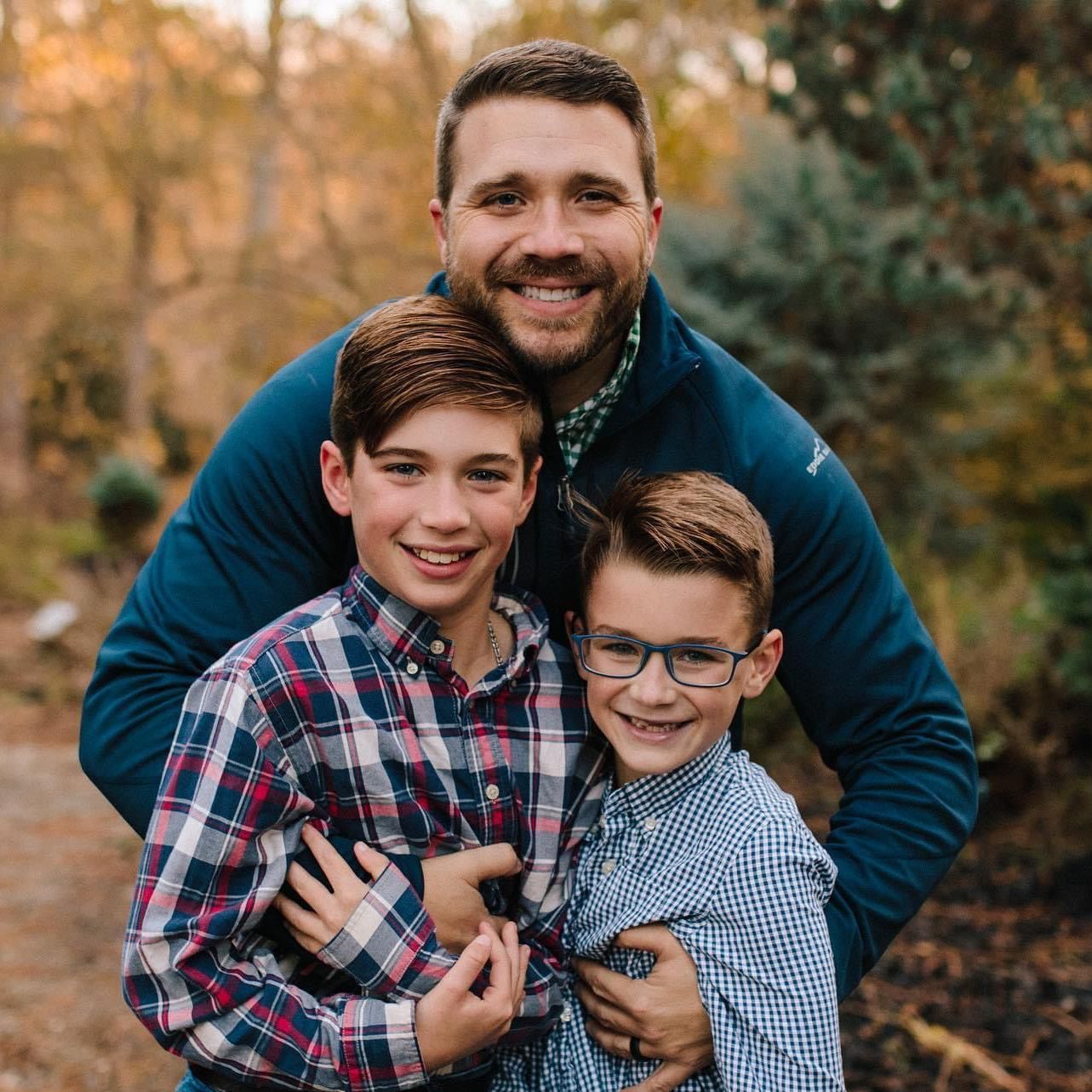A man is posing for a picture with two young boys.