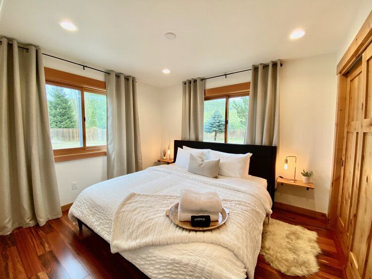 A bedroom with a king size bed and two windows.