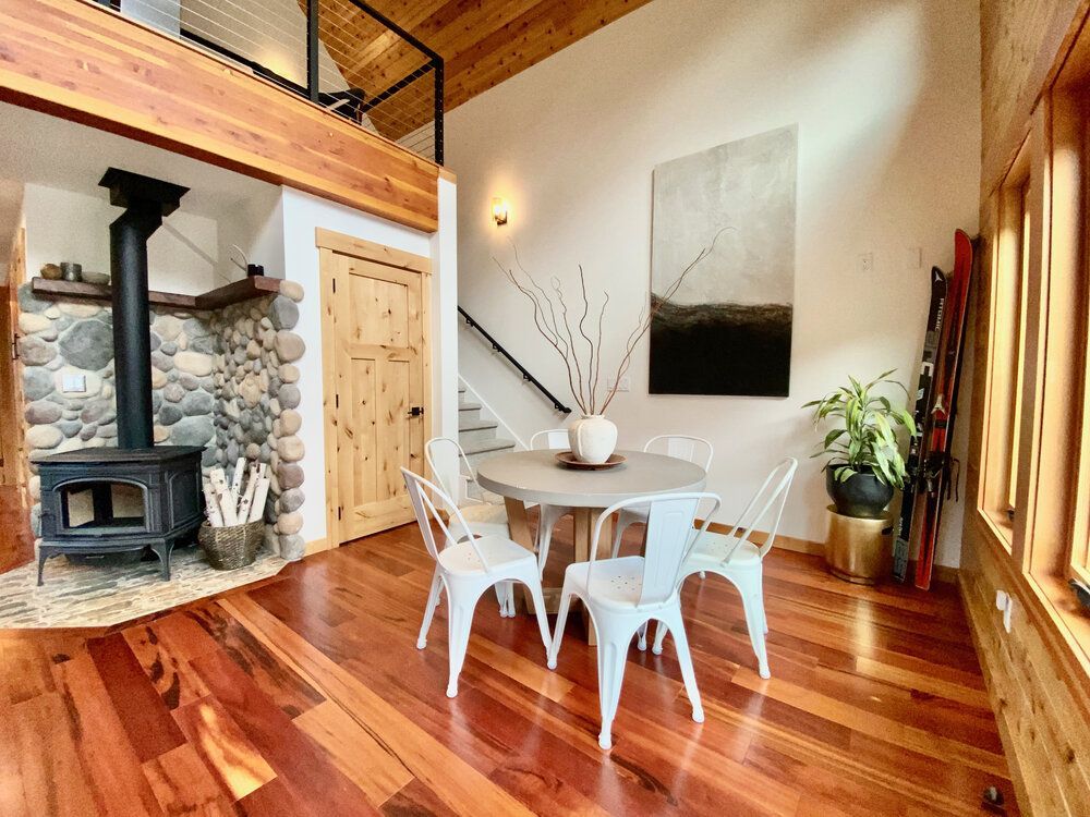 A living room with a wood stove and a table and chairs.