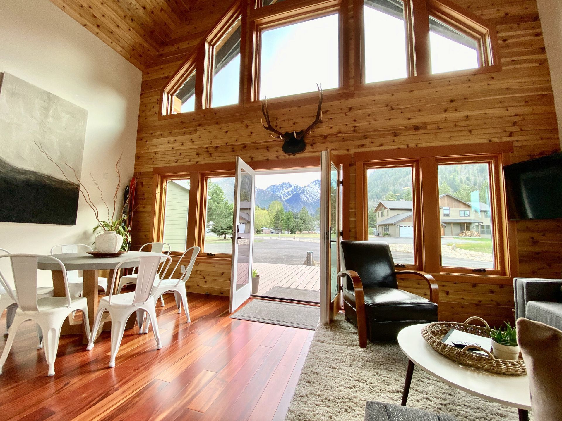 A living room and dining room with deer antlers on the wall.