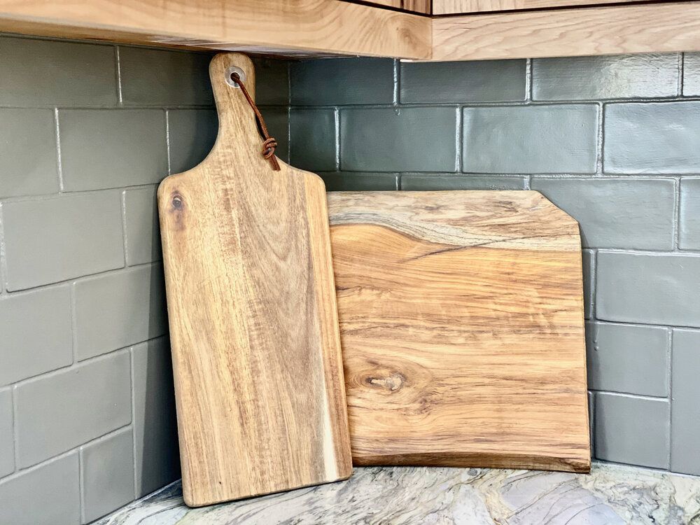 Two wooden cutting boards 
sitting on a counter in a kitchen.