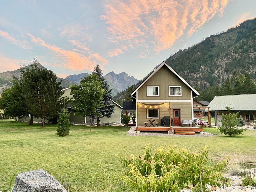 A house with a large lawn in front of it and mountains in the background.