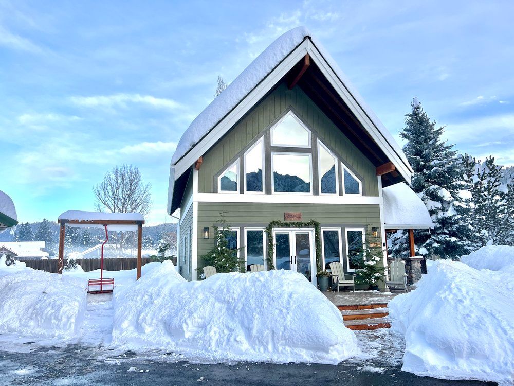A large, snowy, house with a lot of snow on the ground.