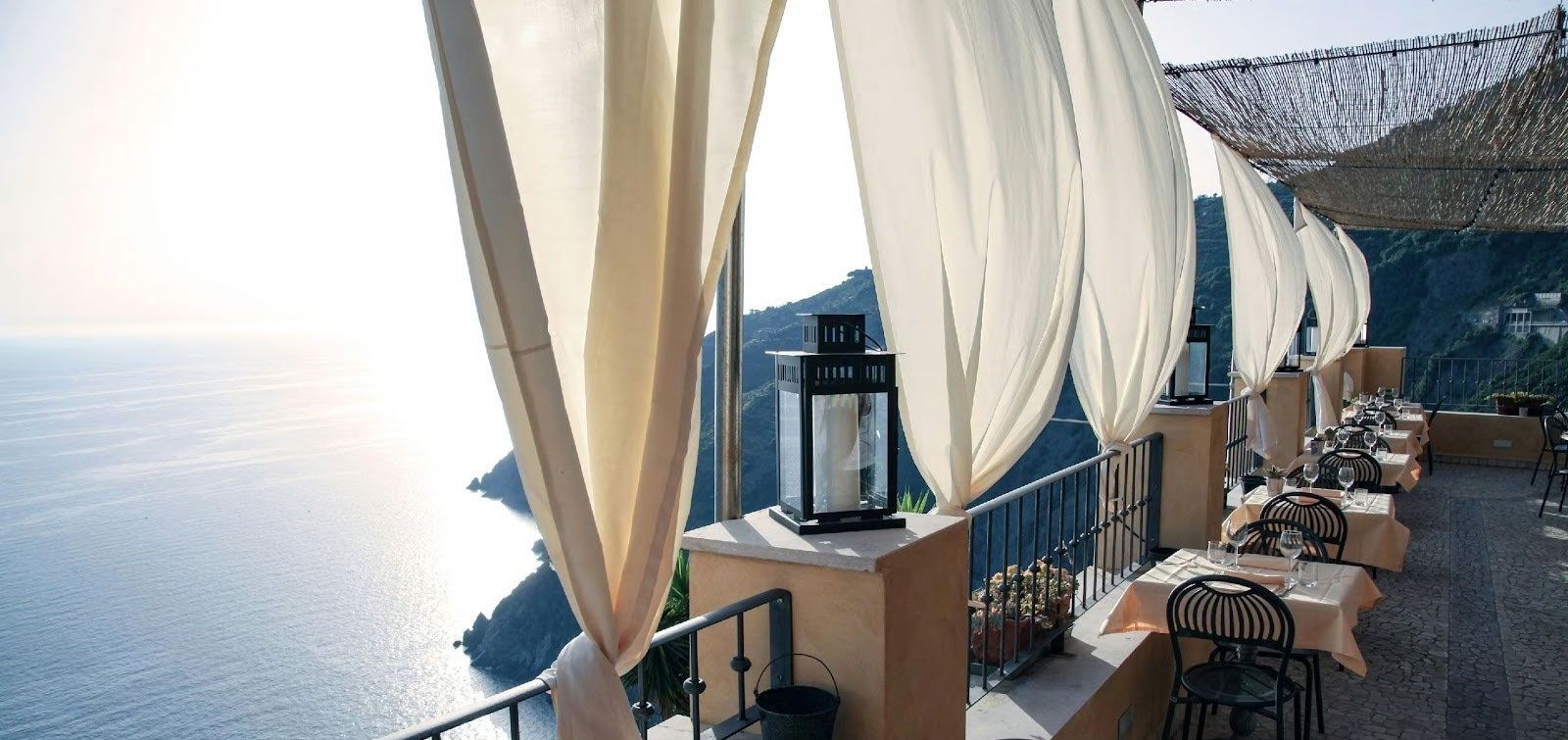 Seaside terrace with white cabanas, tables, and chairs overlooking the ocean
