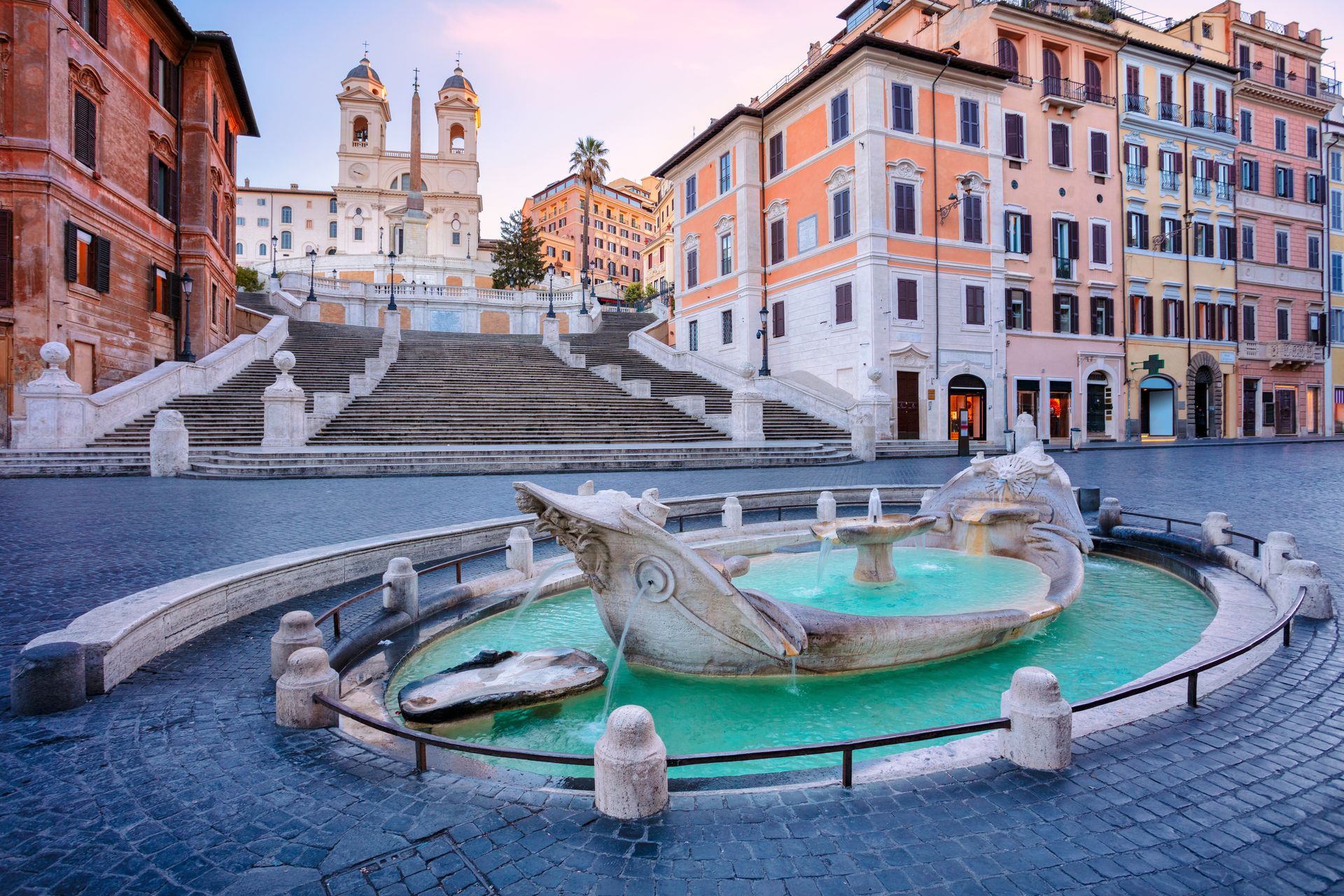 Spanish Steps and Barcaccia Fountain in Rome with pastel buildings under a blue sky