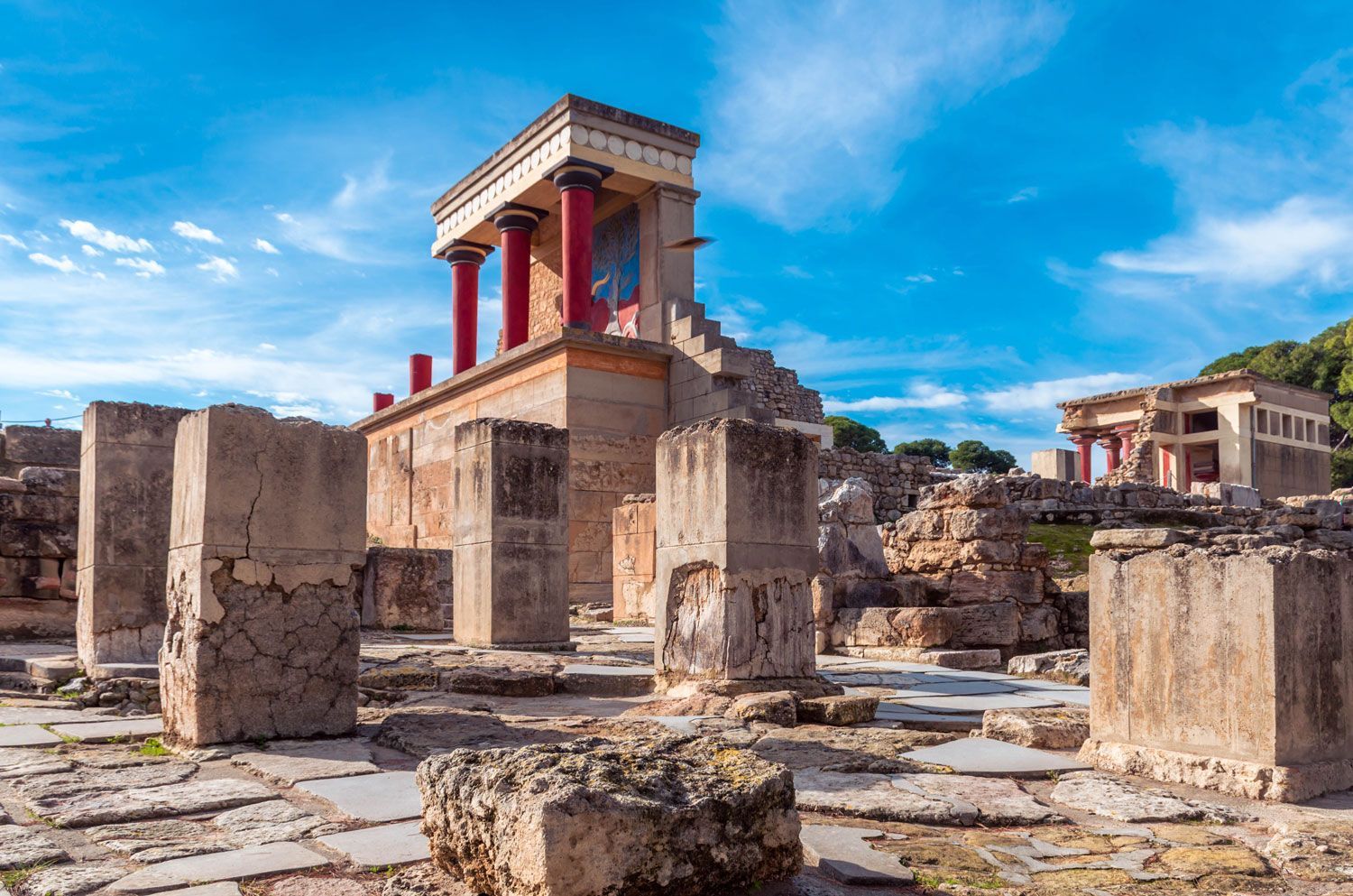 Ancient stone ruins with red columns and a blue sky overhead