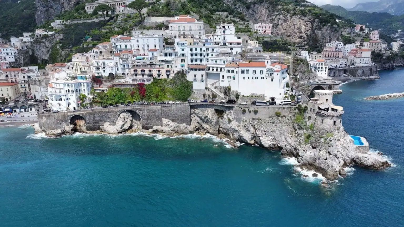 Cliffside coastal town with white buildings overlooking turquoise water and rocky shoreline Cliffside coastal town with white buildings overlooking turquoise water and rocky shoreline
