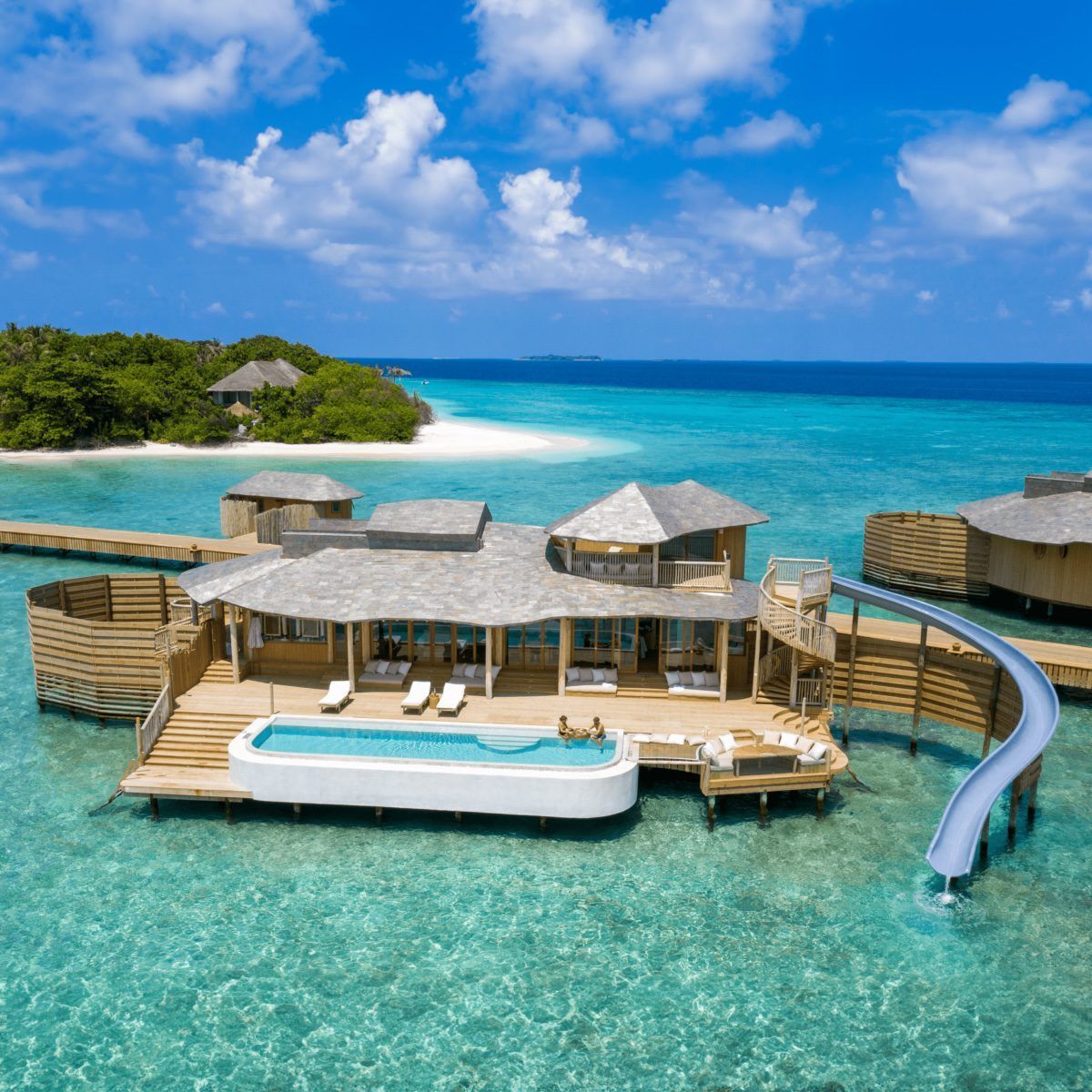 Luxury overwater resort villas in turquoise tropical lagoon under a bright blue sky