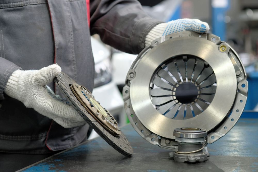 A Man Is Holding A Clutch Plate In His Hands — NQPT In Garbutt, QLD