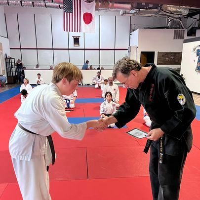 Two men are shaking hands in a karate gym.