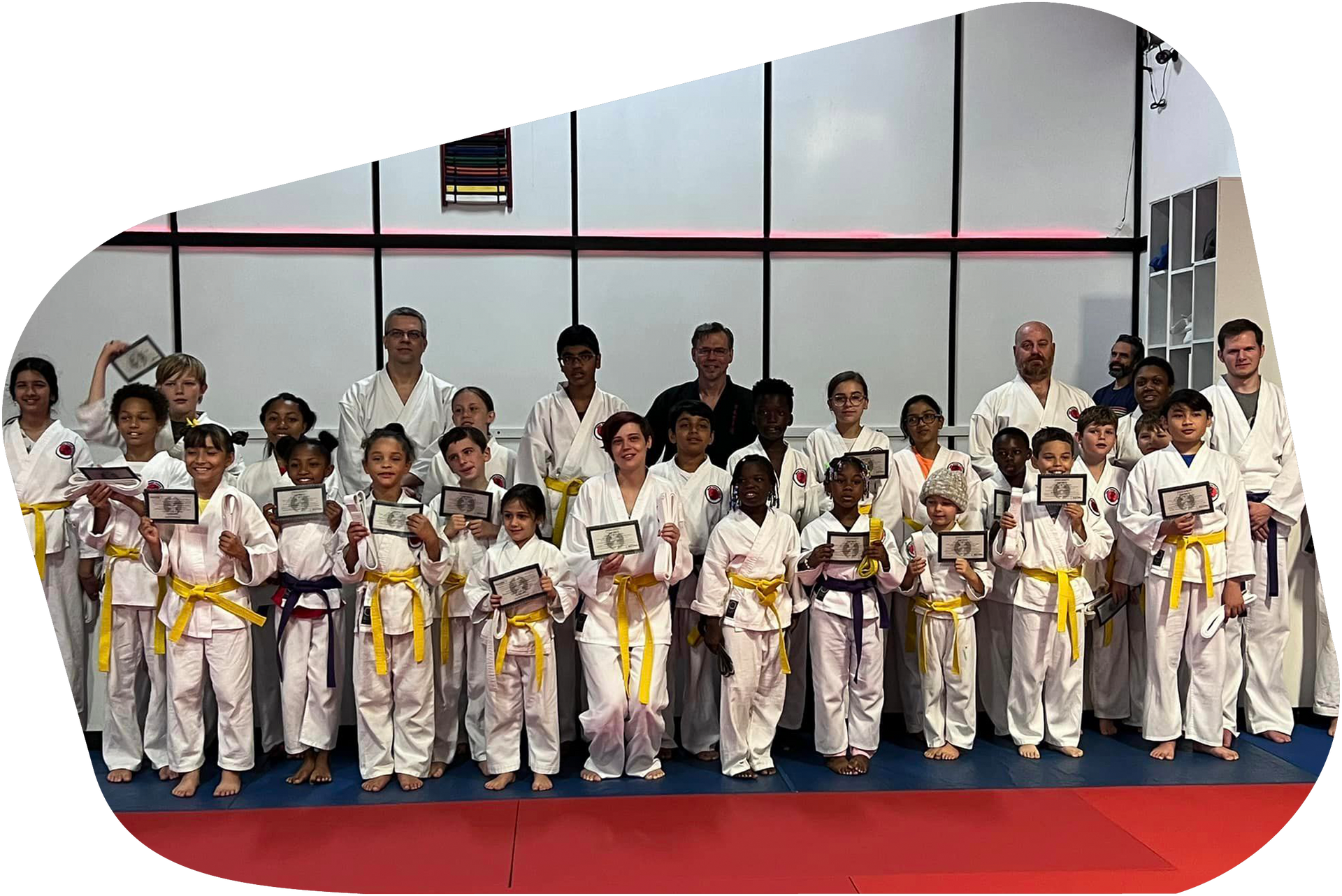 A group of children in karate uniforms are posing for a picture in a gym.