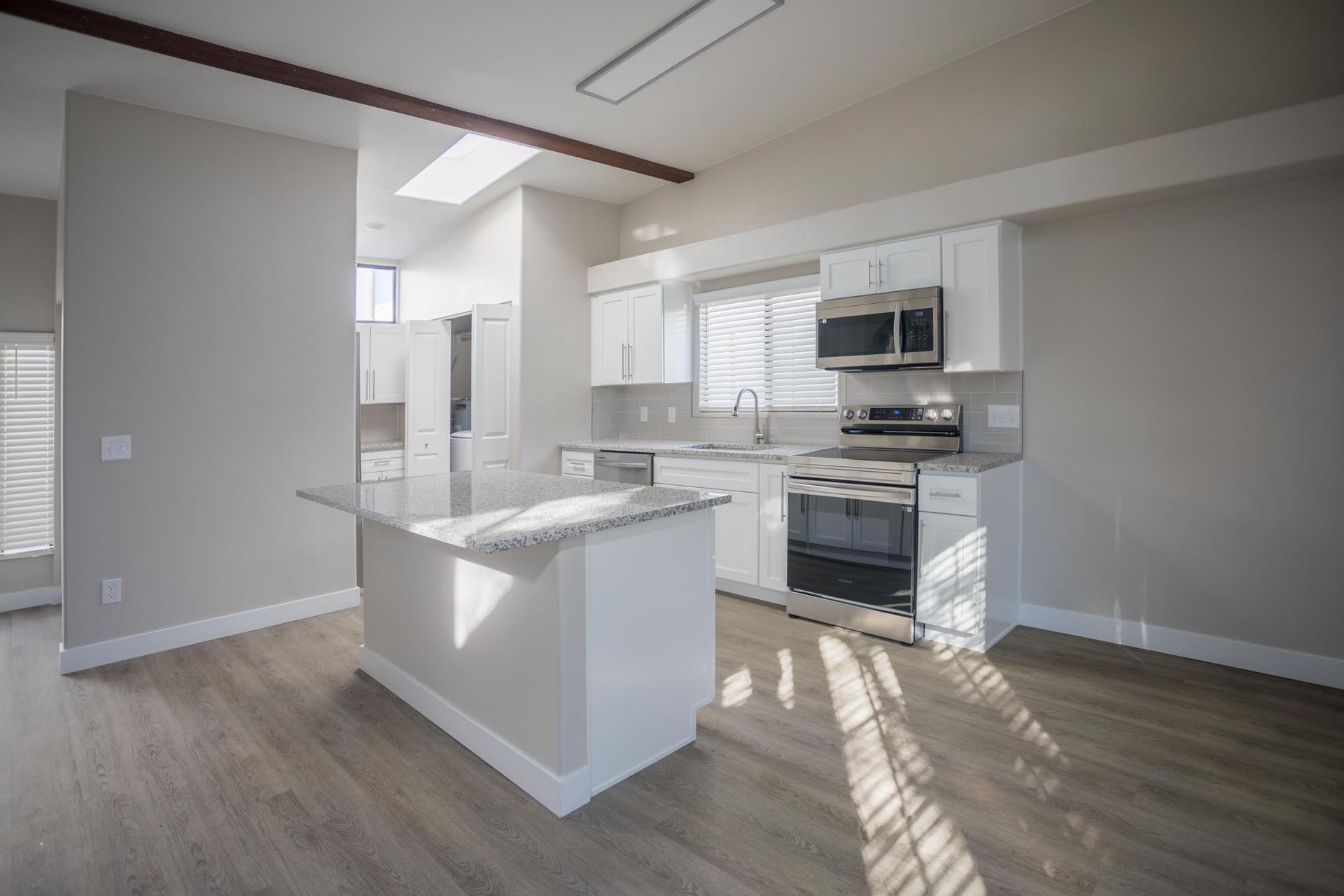 A kitchen with white cabinets , stainless steel appliances , and a large island.