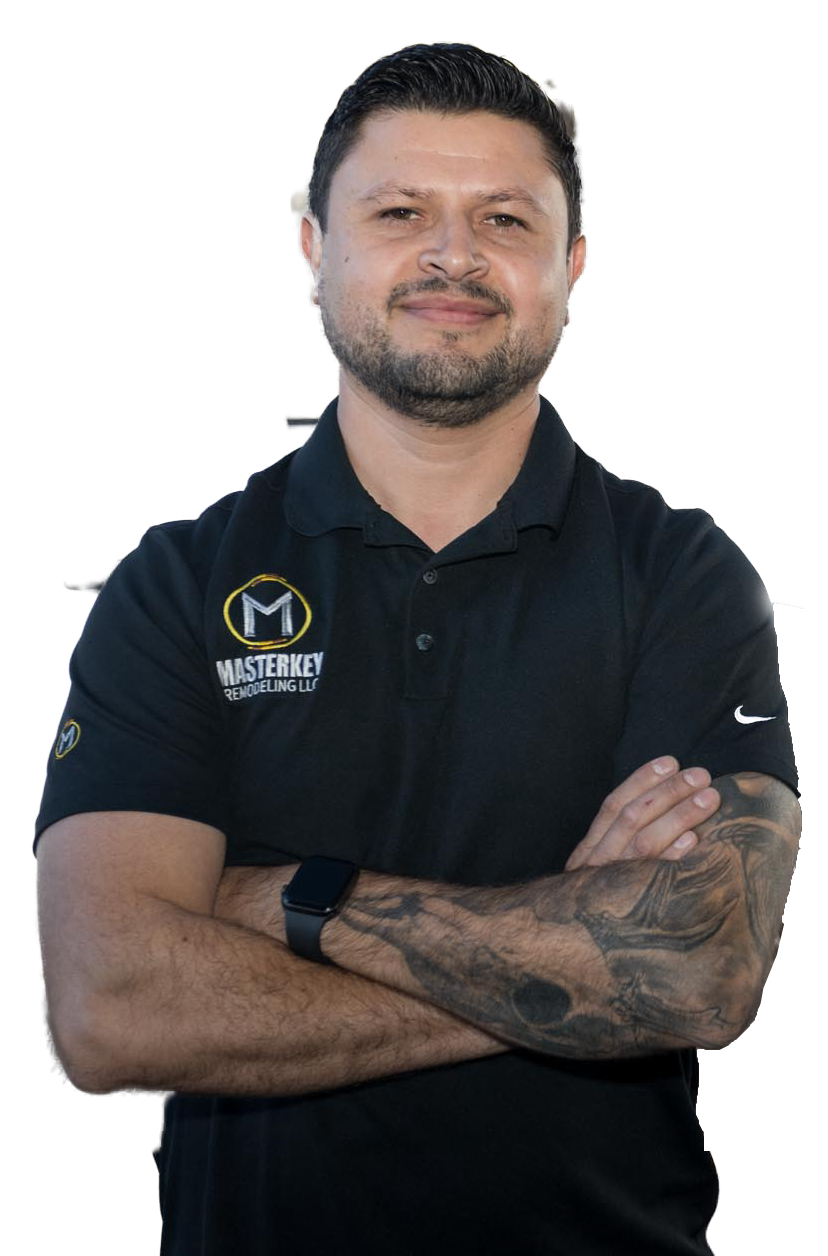 A man with a beard and tattoos is standing with his arms crossed.