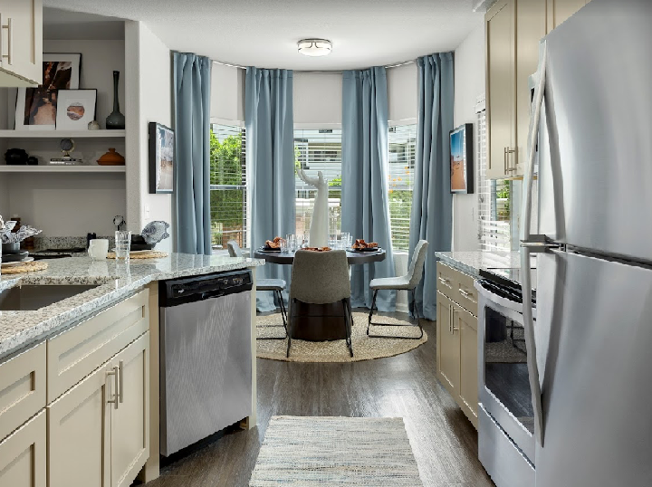 A kitchen with stainless steel appliances and a dining room in the background.