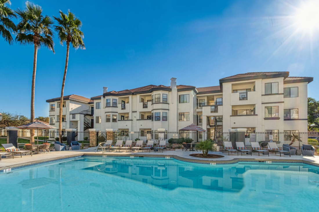 A large apartment building with a large swimming pool in front of it.