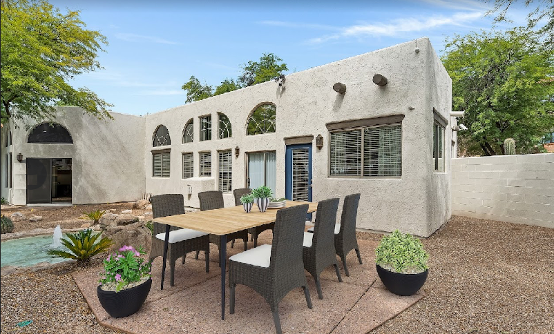 A patio with a table and chairs in front of a house.
