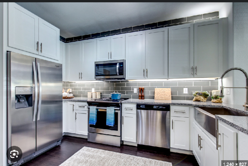 A kitchen with stainless steel appliances and white cabinets.