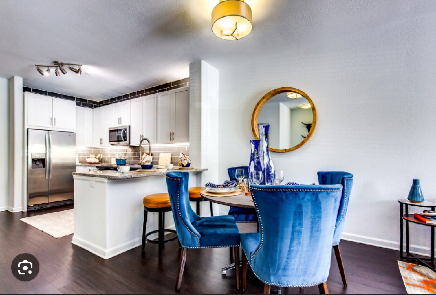 A dining room with blue chairs and a round mirror