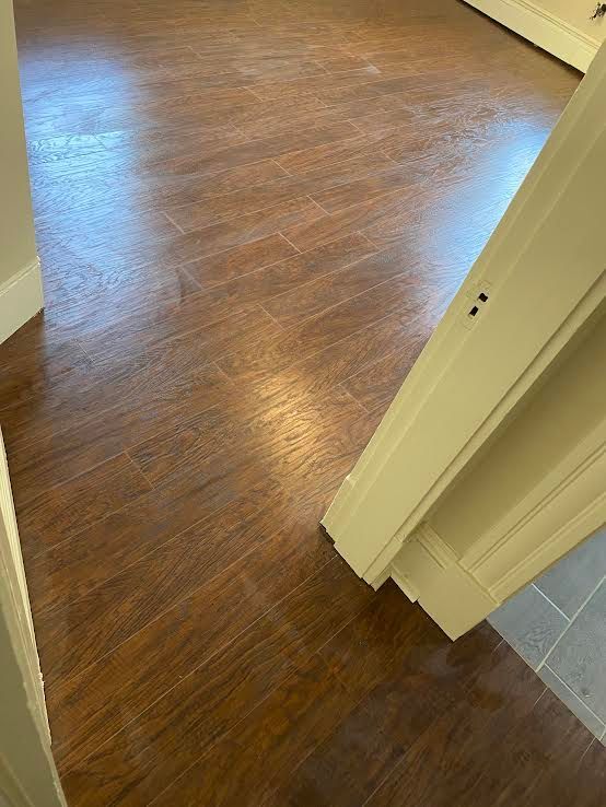 A view from a doorway looking onto brown, wood-look plank flooring.