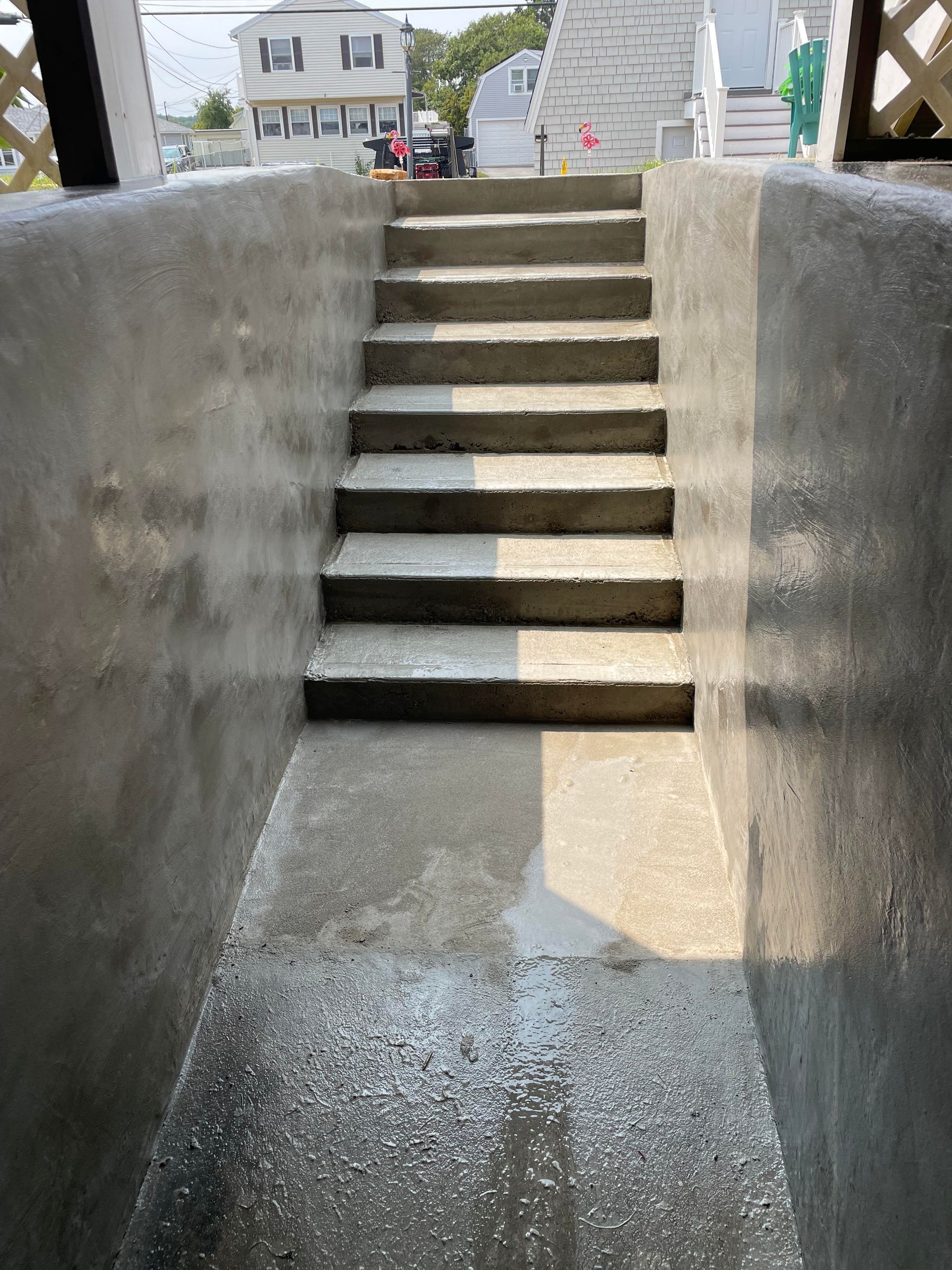 A concrete outdoor staircase leading up from a basement or sunken walkway between two high concrete walls.