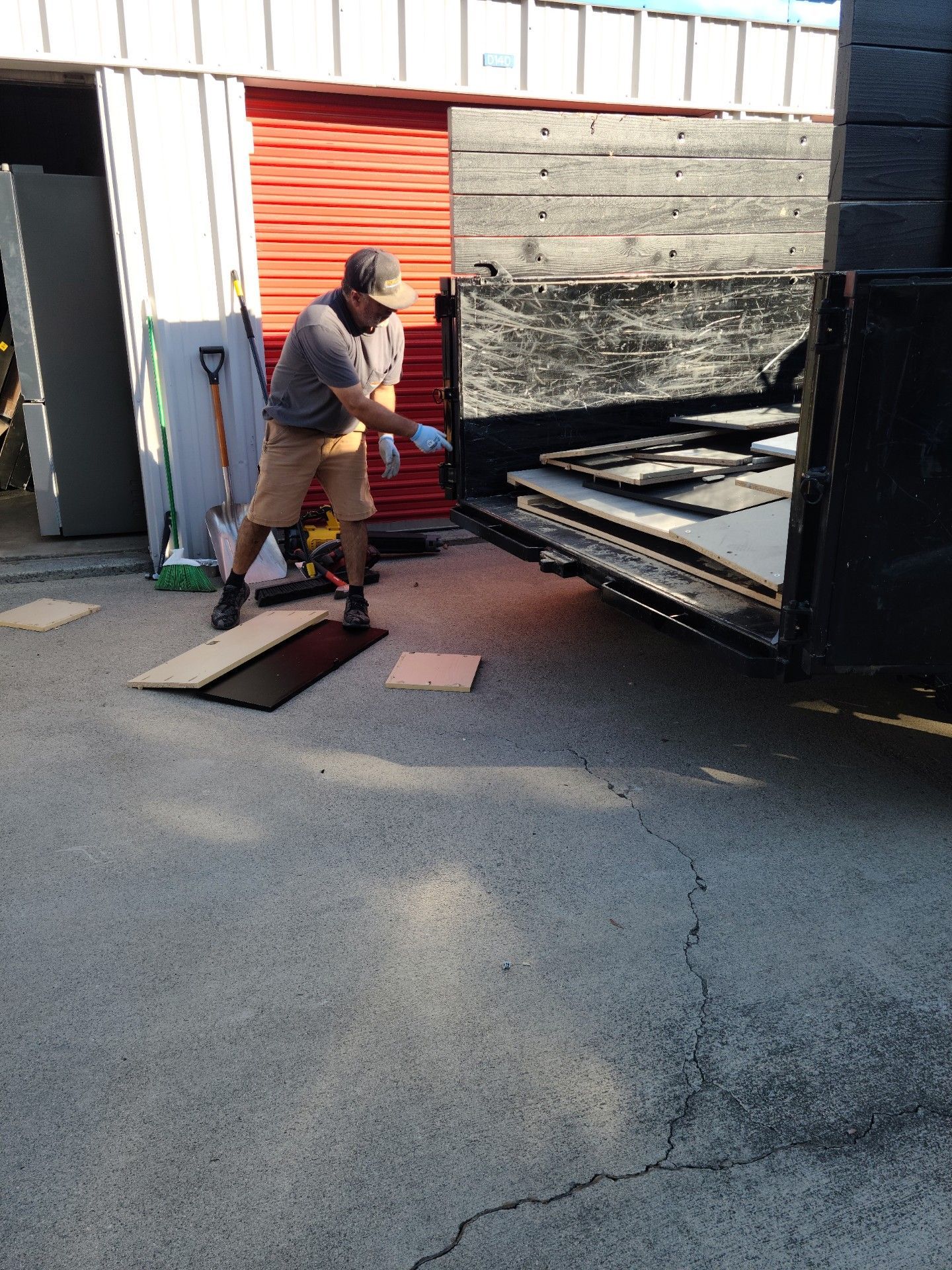 Man unloading materials into a dumpster outside a building.