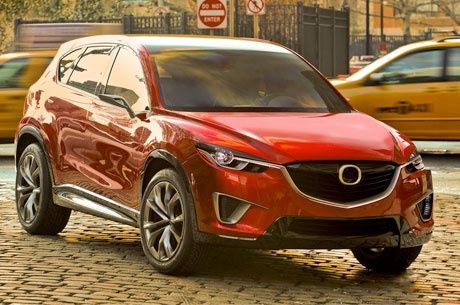 A red mazda cx-5 concept car is parked on a cobblestone street.