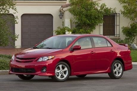 A red car is parked in front of a garage door.