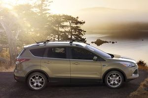 A ford escape is parked on the side of a road next to a lake.