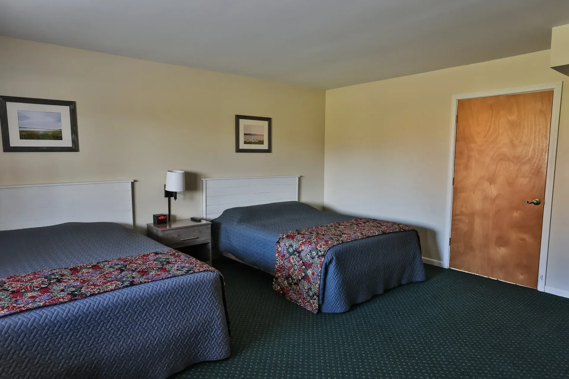 A hotel room with two beds and a door