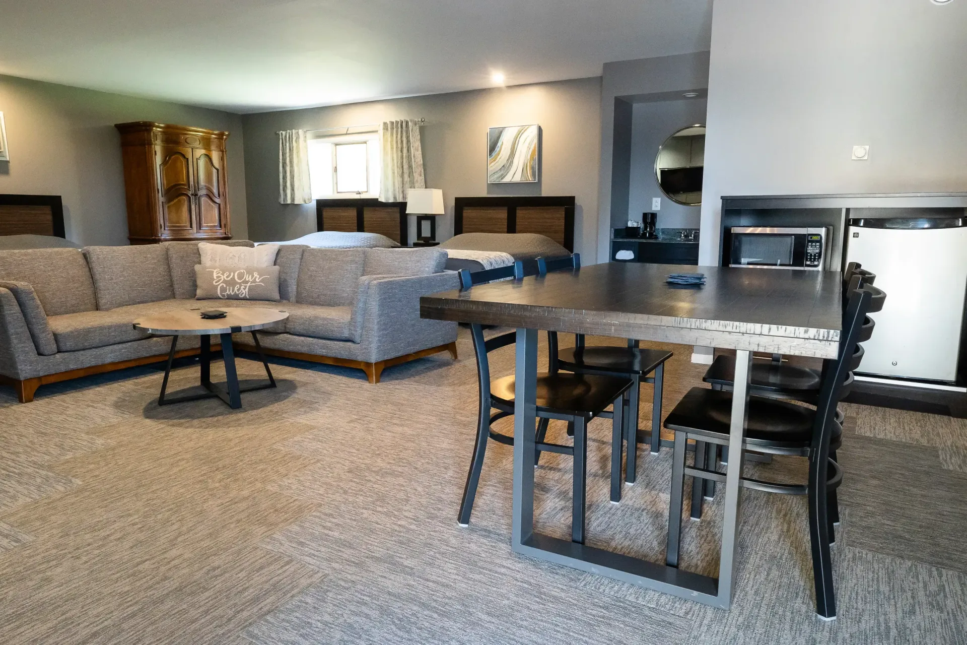 A hotel room with a couch , table and chairs.