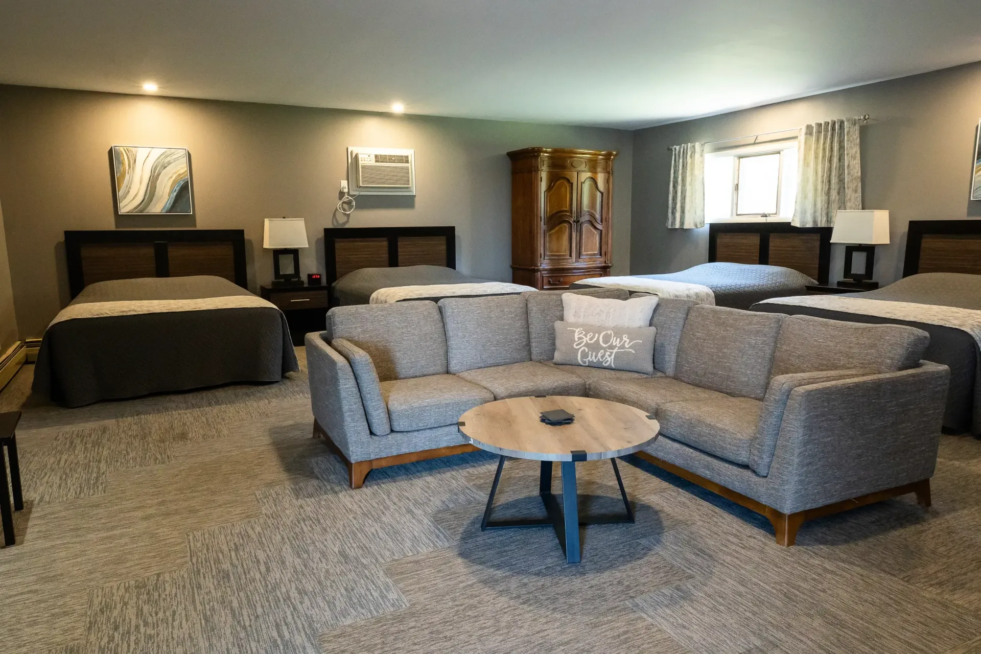 A hotel room with four beds , a couch , and a coffee table.
