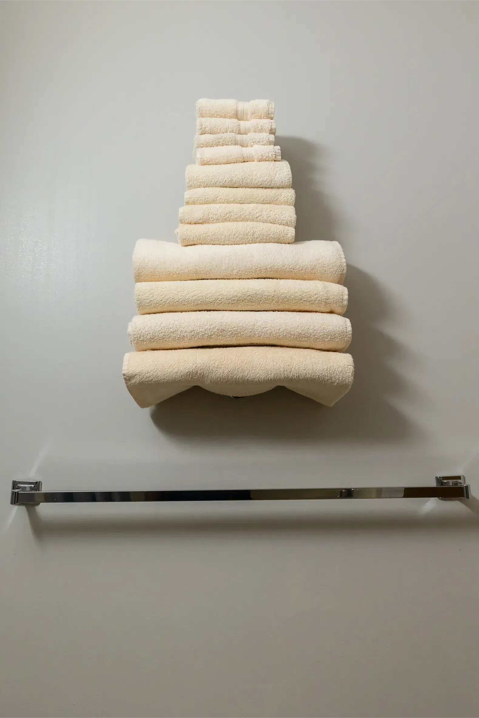 A stack of towels hanging on a wall next to a towel rack.